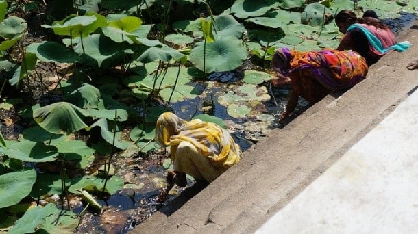 Women blessing themselves in the water in front of the temple