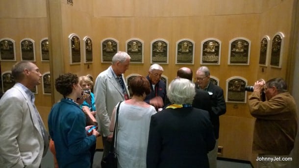 Phil Niekro showing guests how to throw a knuckleball in front of his plaque at the Baseball Hall of Fame for Tauck Events