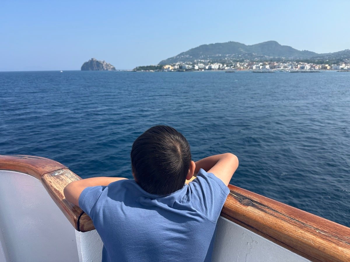Boy on ferry looking at the island of Ischia