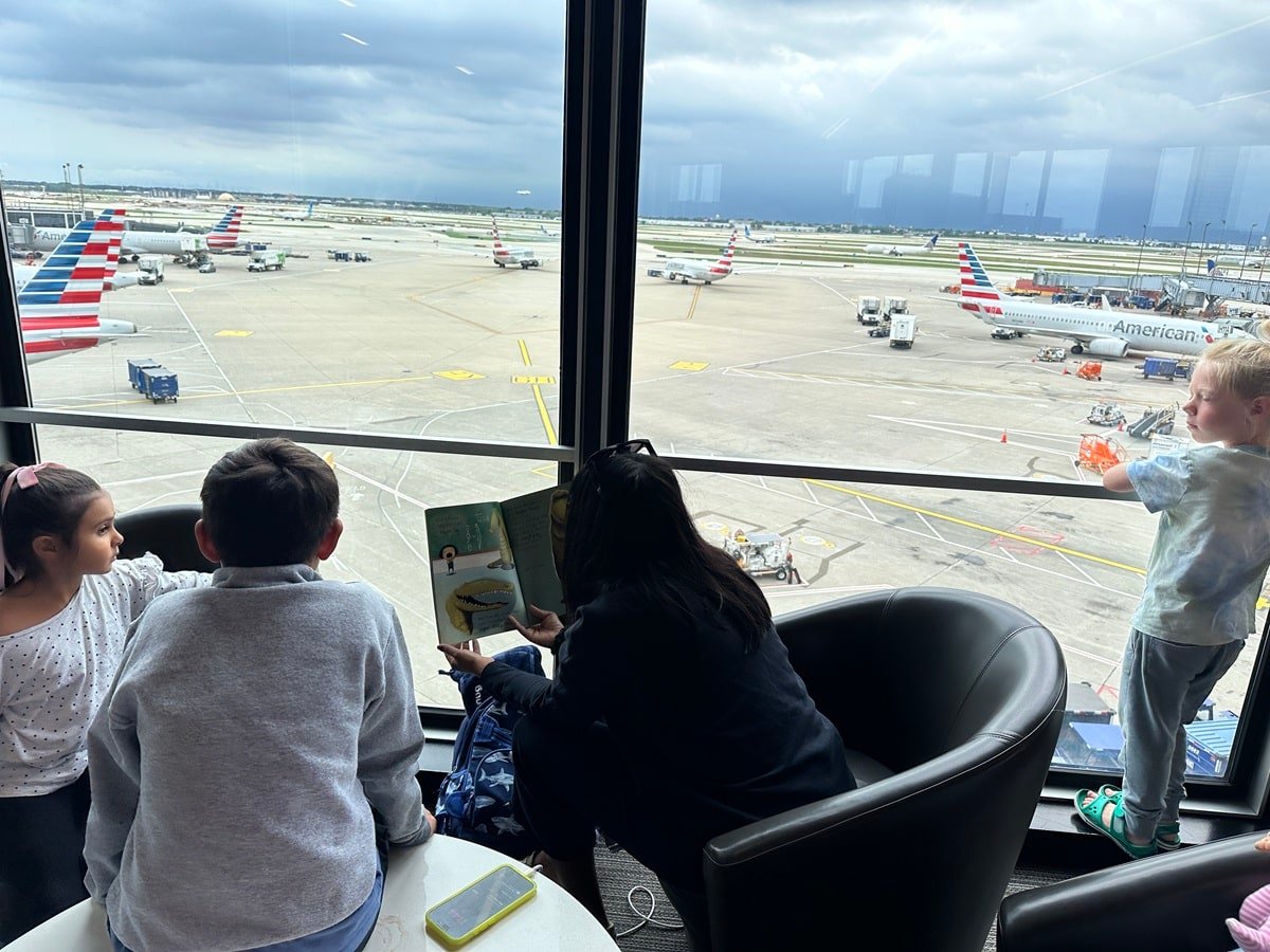 Mother reading to kids in the lounge overlooking runway
