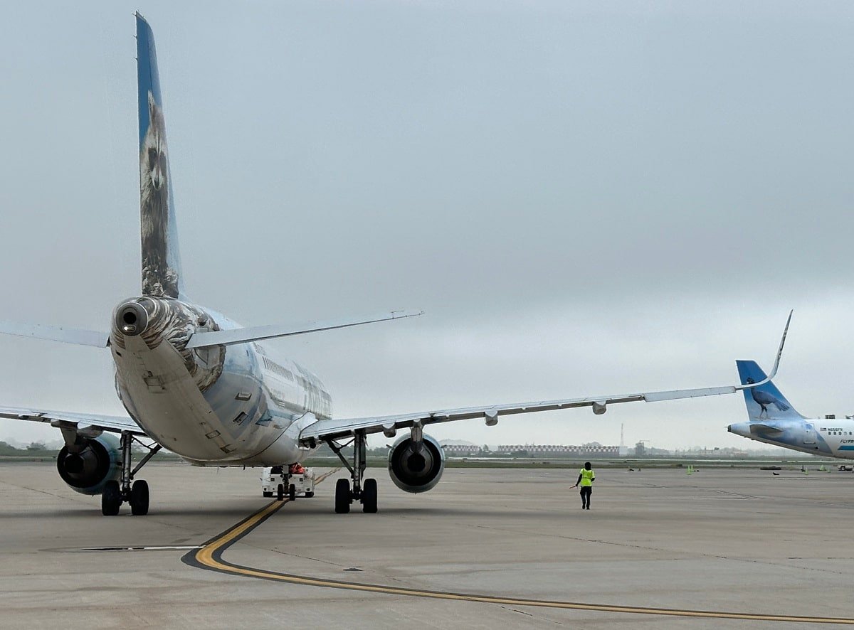 Frontier Airlines plane on the tarmac with another Frontier tail wing nearby