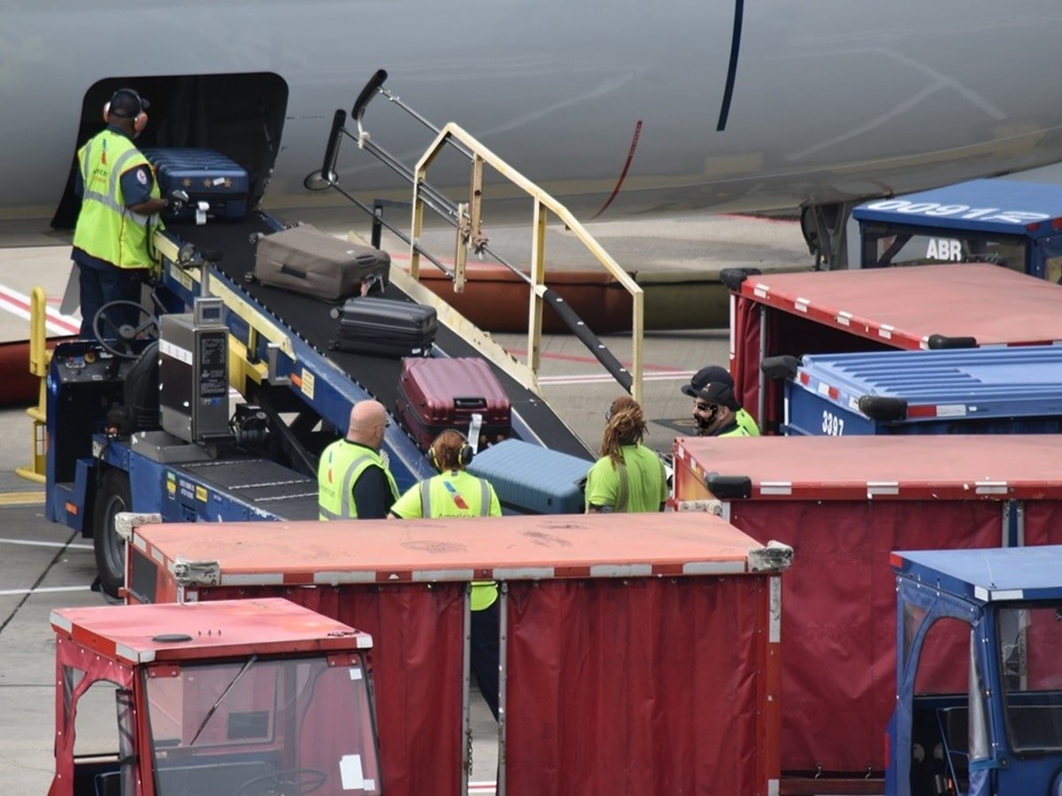 American Airlines Baggage Handlers scanning checked bags going on plane