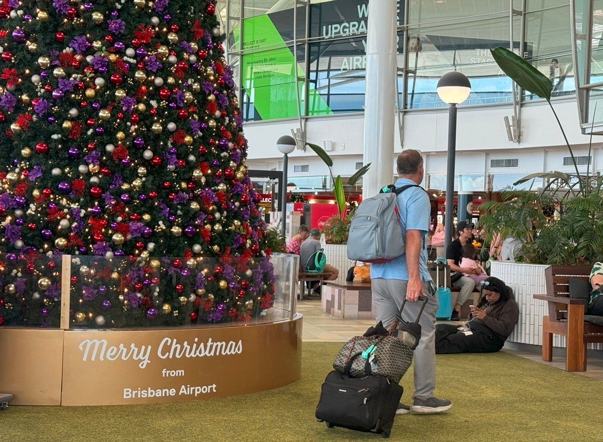 Traveler with bags walking by Christmas tree in an airport