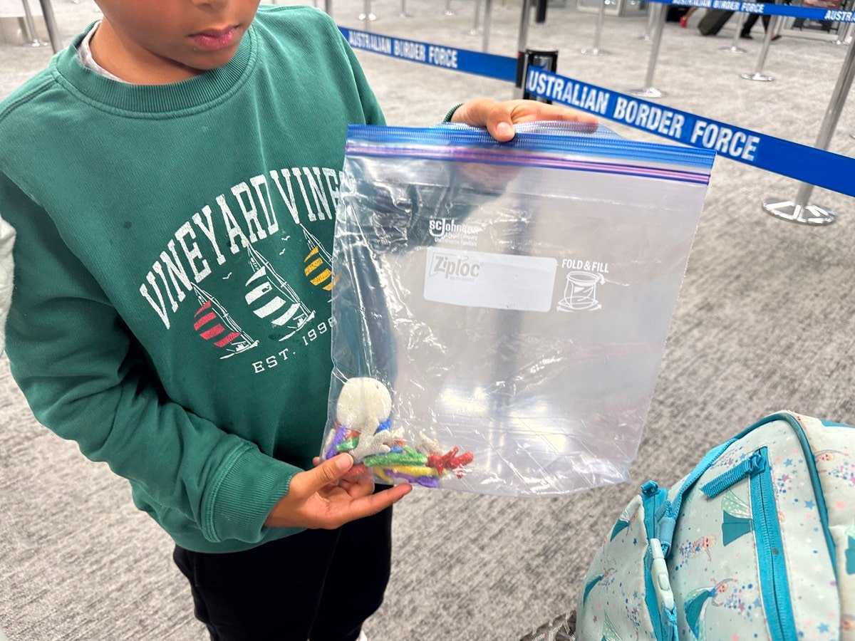 A boy carrying colored dead coral in a plastic bag